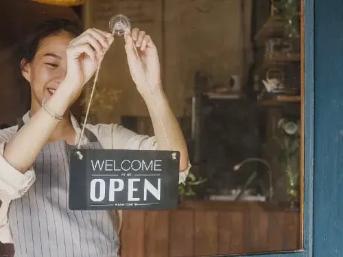 Small business owner places open sign on door